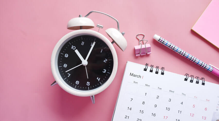 A timetable and clock on a pink background